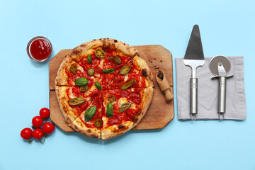 Composition with tasty pizza, spatula and cutter on blue background