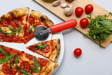 Composition with tasty pizza, ingredients and cutter on grey background