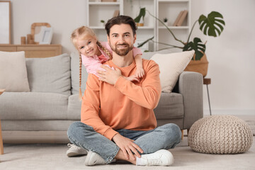 Obraz premium Cute little girl hugging her father while sitting on floor at home. International Hug Day