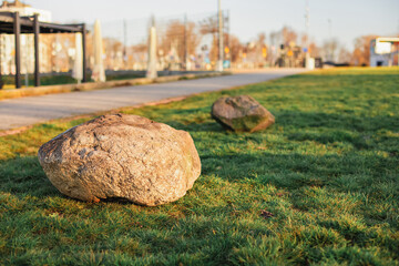 
A large stone lies on the grass in the park, landscaping, a big problem to solve