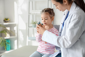 Female pediatrician and cute little girl with inhaler in clinic