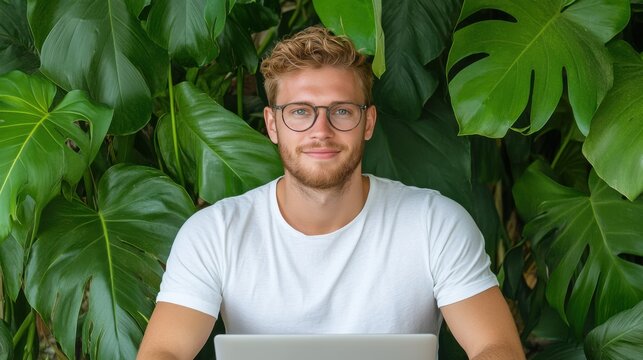 Young man working on laptop amidst lush greenery urban jungle digital workspace natural light inspirational concept