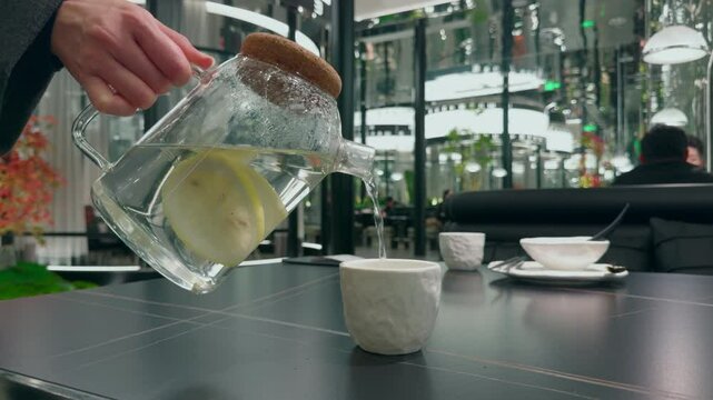 Pouring lemon water from a pitcher into a glass.