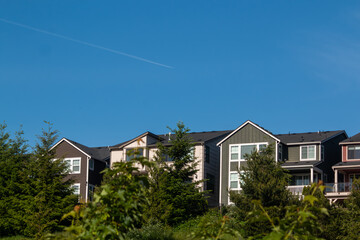 Modern homes with a jet airliner flying across the clear blue sky
