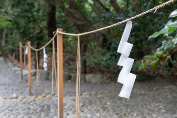 A traditional shimenawa rope, made of twisted hemp fibers and adorned with shide ornaments,...