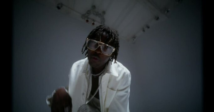 The rapper is recording video clip in the studio. He dances and sings looking at the camera