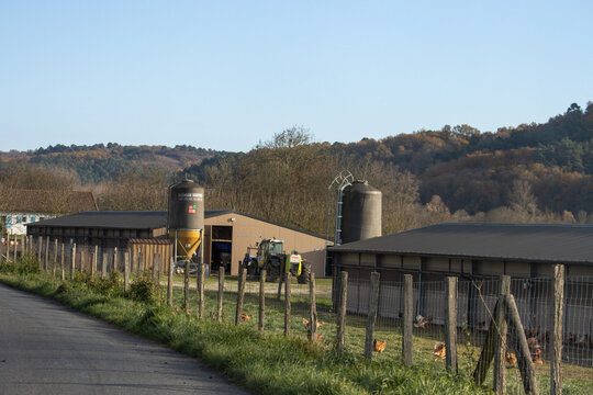 France, 27 November 2024 : Tractor near farm buildings with silo and fence visible