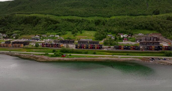 Scenic homes along Tromso&rsquo;s Road E8 in Norway surrounded by lush green landscapes and mountains, aerial approach over water