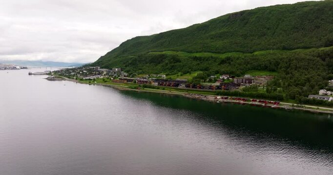 Road E8 in Tromso Norway with scenic homes and stunning mountain backdrop, aerial slow approach