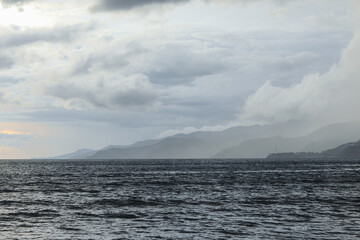 Seascape with cloudy sky and mountains in the background at sunset