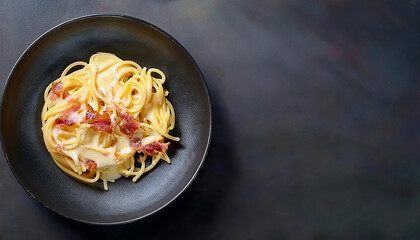 Linguini pasta with carbonara sauce on a dark background. Carbonara sauce made of bacon, parmesan, eggs, cream and pepper. Italian food.