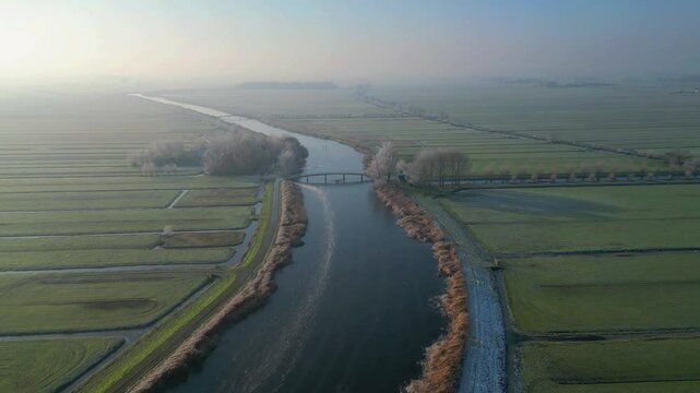 Winter landscape with a frozen river seen from above. A vast plain full of Dutch water canals seen from the drone early in the morning in Netherlands