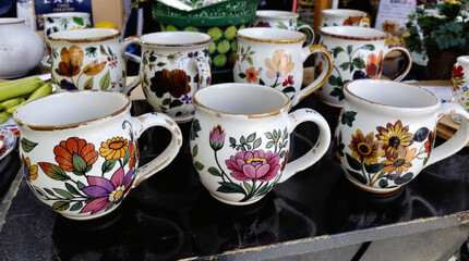 Fototapeta premium Handmade pottery mugs with floral designs on a table