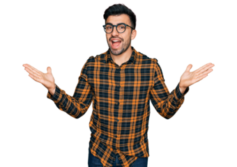Hispanic man with beard wearing casual clothes and glasses celebrating victory with happy smile and winner expression with raised hands