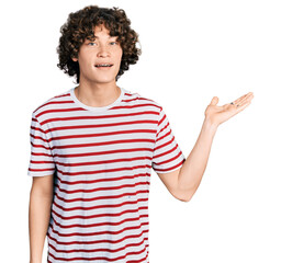 Caucasian teenager wearing casual clothes smiling cheerful presenting and pointing with palm of hand looking at the camera.
