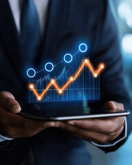 Businessman holding a tablet with a digital graph displaying growth trends and analytics for decision making.