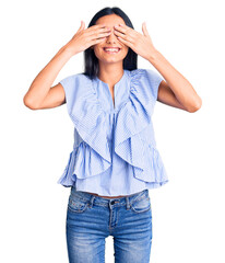 Young beautiful latin girl wearing casual clothes covering eyes with hands smiling cheerful and...