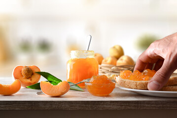 Hand picking up toast with peach jam on wooden bench