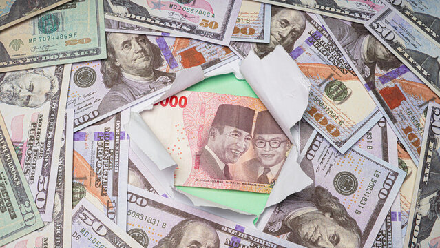 one hundred thousand Indonesian rupiah banknotes amidst torn paper and piles of dollar bills