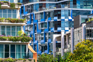 This image captures a visually striking collection of residential buildings with innovative designs, emphasizing curves, symmetry, and bright colors within a lively urban setting in Amsterdam