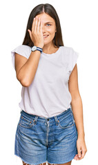 Obraz premium Young caucasian woman wearing casual white tshirt covering one eye with hand, confident smile on face and surprise emotion.