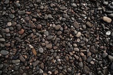 Natural background of wet gray sea pebbles. Abstract pebble texture on the sea beach. Sea pebbles. Variety of smooth, natural stones with different shapes and on the seacoast. Wet stones backdrop.