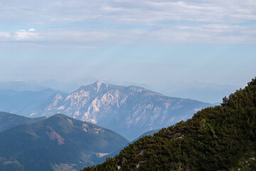 Hiking trail with scenic view of rugged mountain peak Dobratsch in Julian Alps seen from Triglav National Park, Vrsic pass, Slovenia. Wanderlust wild Slovenian Alps. Distant view of Austrian landscape