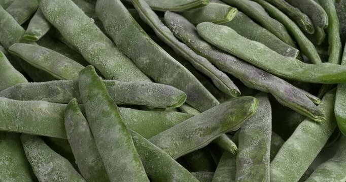 Frozen whole young cranberry bean pods background. Table spin. 