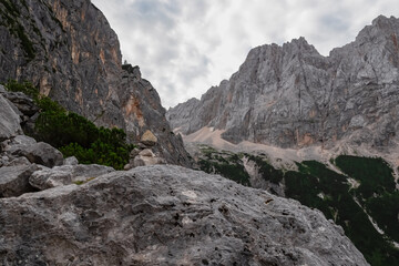 Fototapeta premium Hiking trail with scenic view of rugged mountain peak Skrlatica in Julian Alps seen from Krnica valley, Vrsic pass, Slovenia. Wanderlust wild Slovenian Alps. Ridges with sharp edges and steep cliffs