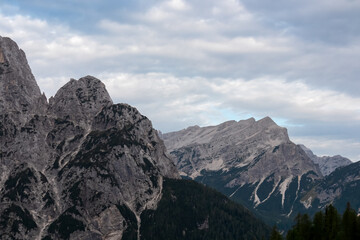 Obraz premium Hiking trail with scenic view of rugged mountain peak Mojstrovska in Julian Alps seen from Krnica valley, Vrsic pass, Slovenia. Wanderlust wild Slovenian Alps. Ridges with sharp edges and steep cliffs