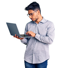 Handsome latin american young man working using computer laptop thinking attitude and sober...