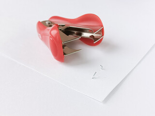 Staple remover and a sheet of paper with staples are lying on the table. Close-up of the staple...