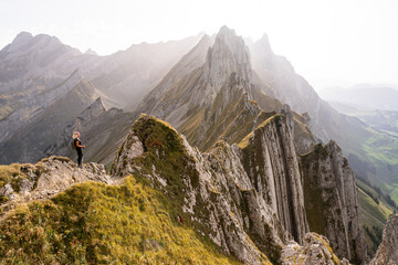 Young woman hiking in Appenzell Innerrhoden canton of Swiss Alps, Switzerland. Rocky mountain peaks...