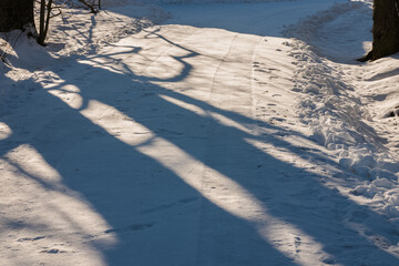 An empty snow-covered country road nearby, car tire tracks, snow shoveled to the ditch on the...