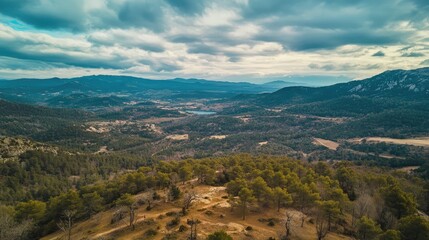 Fototapeta premium Aerial view from a mountain capturing lush valleys and expansive skies under a dramatic cloudscape with a stunning landscape below
