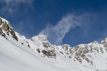 Obraz premium Snow blows off the summit of a mountain in Beehive Basin, a winter scene with blue sky in Montana