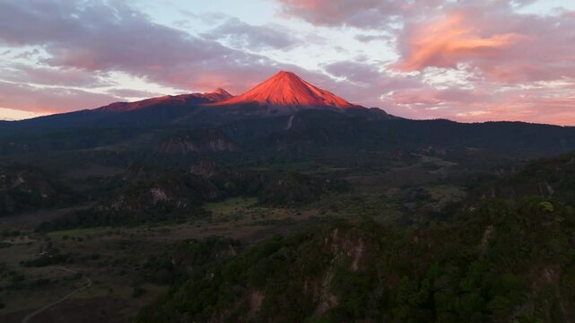 Twilight aerial ascend to Volcan de Colima during sunset with dramatic glowing red orange on volcanic texture