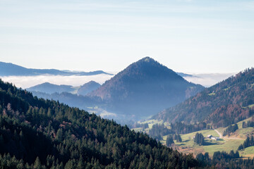 Fototapeta premium Berglandschaft mit Waldhügeln und Nebeldecke im Tal bei klarem Himmel