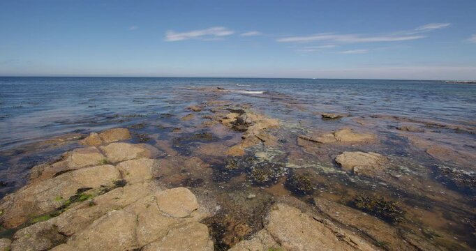 Extra Wide shot of the sea lapping over sedimentary rocks with the tide coming in at Longhoughton beach of the howdiemony sands. Alnwick.