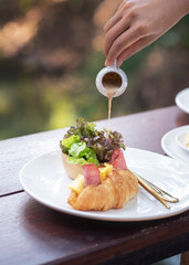 Delicious ham and cheese croissant served with a fresh side salad. The golden, flaky pastry is filled with melted cheese and savory ham, creating a perfect blend of crisp, creamy, and savory flavors