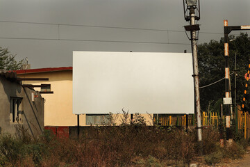 Advertising billboard mockup on the near railway fatak in indian rural areas. Large Hoarding advertising hanging for mockup. Blank white banner for advertisement mounted in india.
