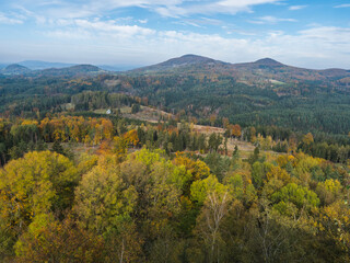 Panoramic view from viewpoint Stredni vrch near Dolni Prysk, Ceska Kamenice. Autumn landscape with colorful forest, hills and blue cloudy sky in Luzicke hory Lusatian Mountains, Czech Republic.