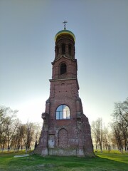 Old Christian Orthodox chapel against blue sky and tree branches