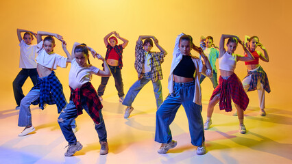Group of teen girl in stylish clothes, jeans, checkered shirts, dynamically dancing hip hop against...