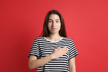 Fototapeta premium Woman making promise on red background. Oath gesture
