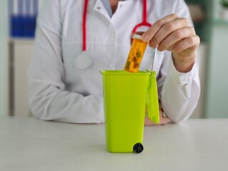 Proper disposal of medication in a green container by a health professional