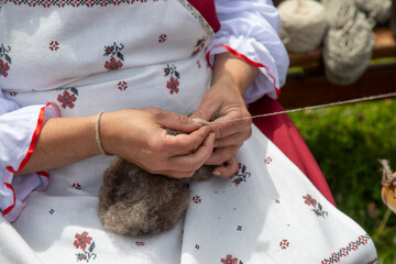 A woman spins woolen thread by hand.