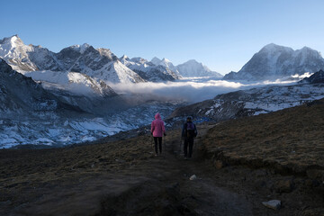 Obraz premium Silhouettes of hiking people and amazing panorama with peaks above clouds from Kala Patthar viewpoint. Everest Base Camp, Sagarmatha National Park, Khumbu valley, Nepal, Himalayas