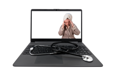 Laptop and medical stethoscope on a transparent background. On the laptop screen - a girl in a bathrobe clasped her head in her hands (headache)