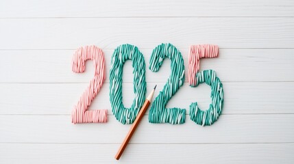 Colorful yarn numbers "2025" with a crochet hook, symbolizing creativity and handmade crafts, set against a light wooden background.